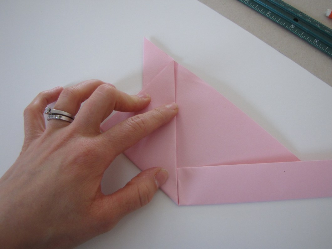 Fold one of the bottom corners up along the crease line.